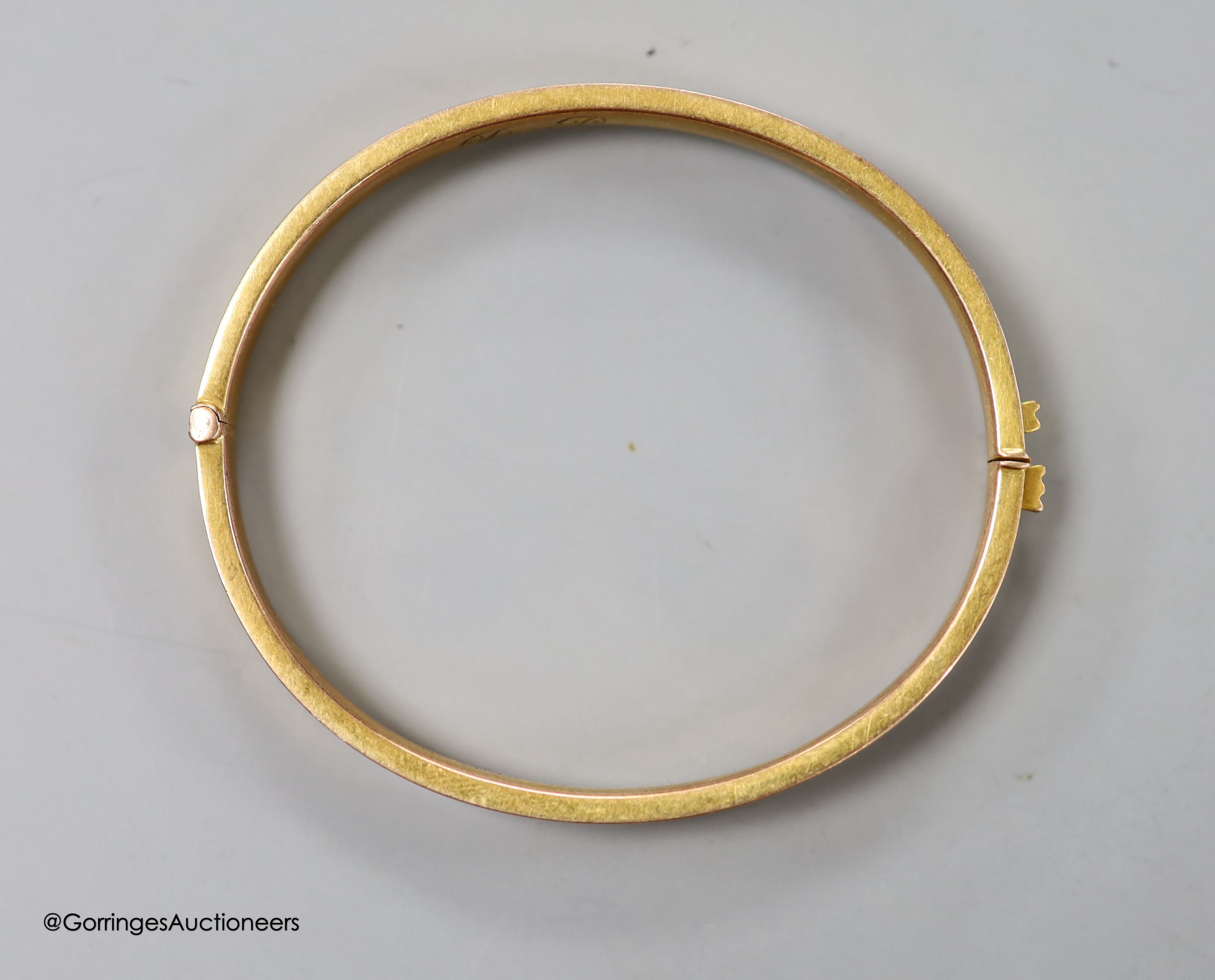 A George V 9ct gold hinged bangle, with engraved initials, 9.1 grams.